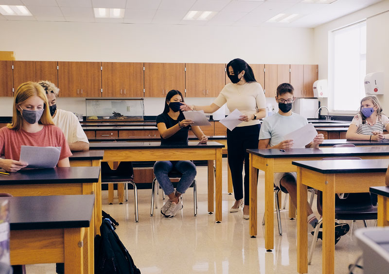 teacher handing student papers in high school science lab